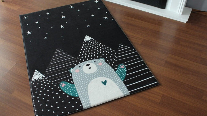 Missia Home children's carpet featuring a whimsical bear design on a black background with mountain patterns.